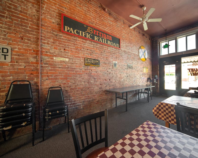 Interior of a restaurant with brick walls, checkered tablecloths, and railroad-themed decor.